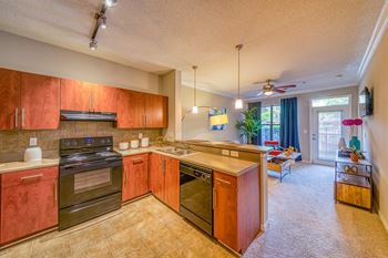 A kitchen with red cabinets and a black stove top oven.